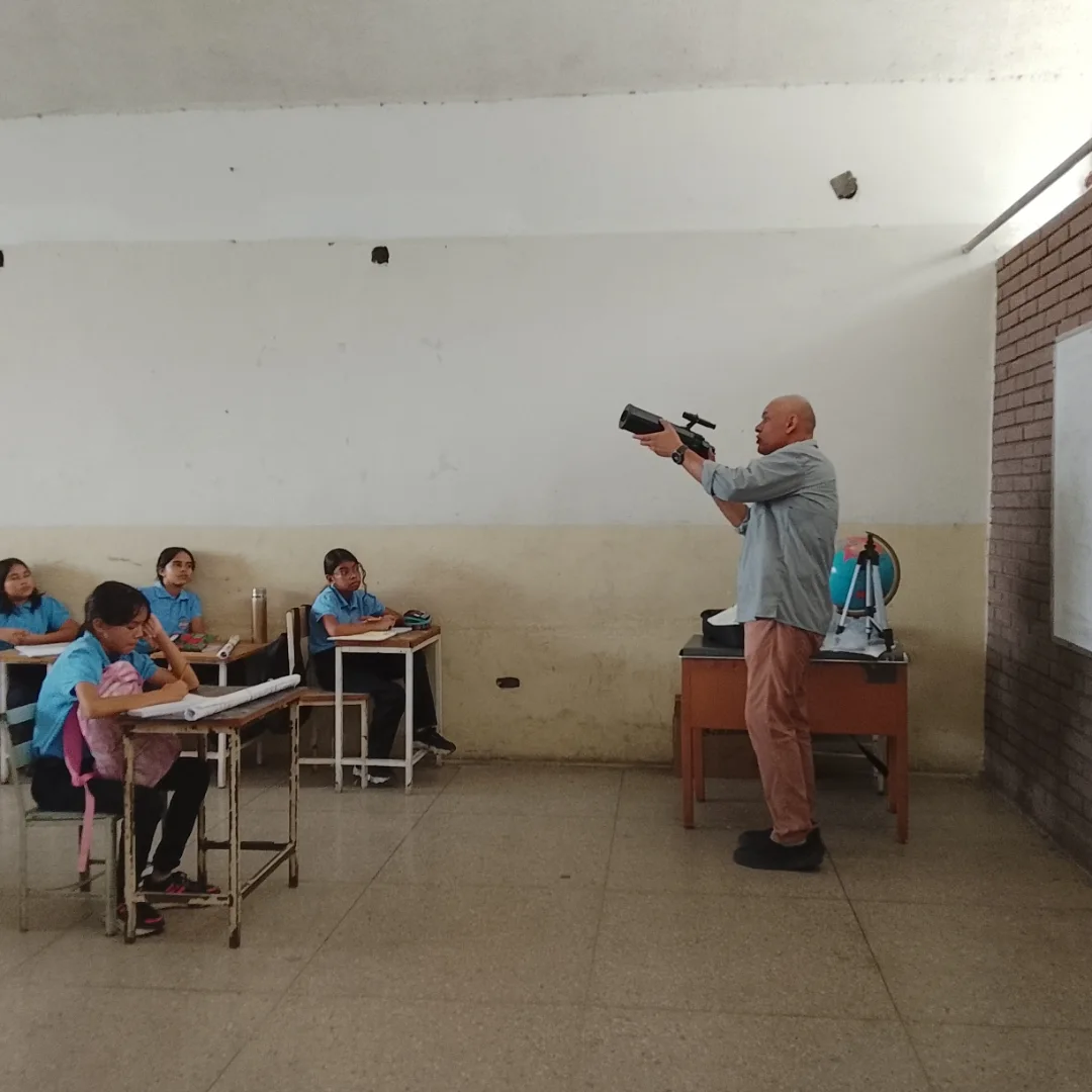 Docente explicando el uso de un telescopio en el salón de clases